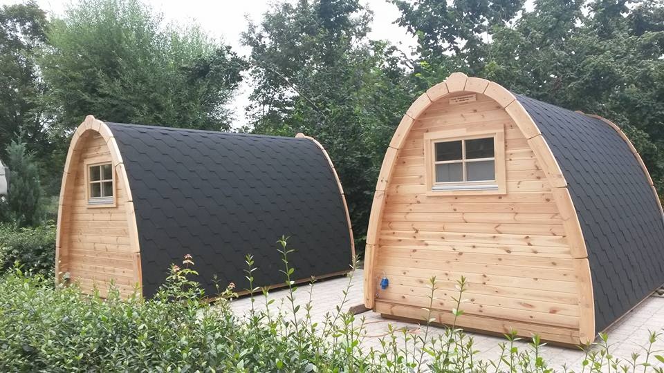 een houten schuurtje naast een zwart dak