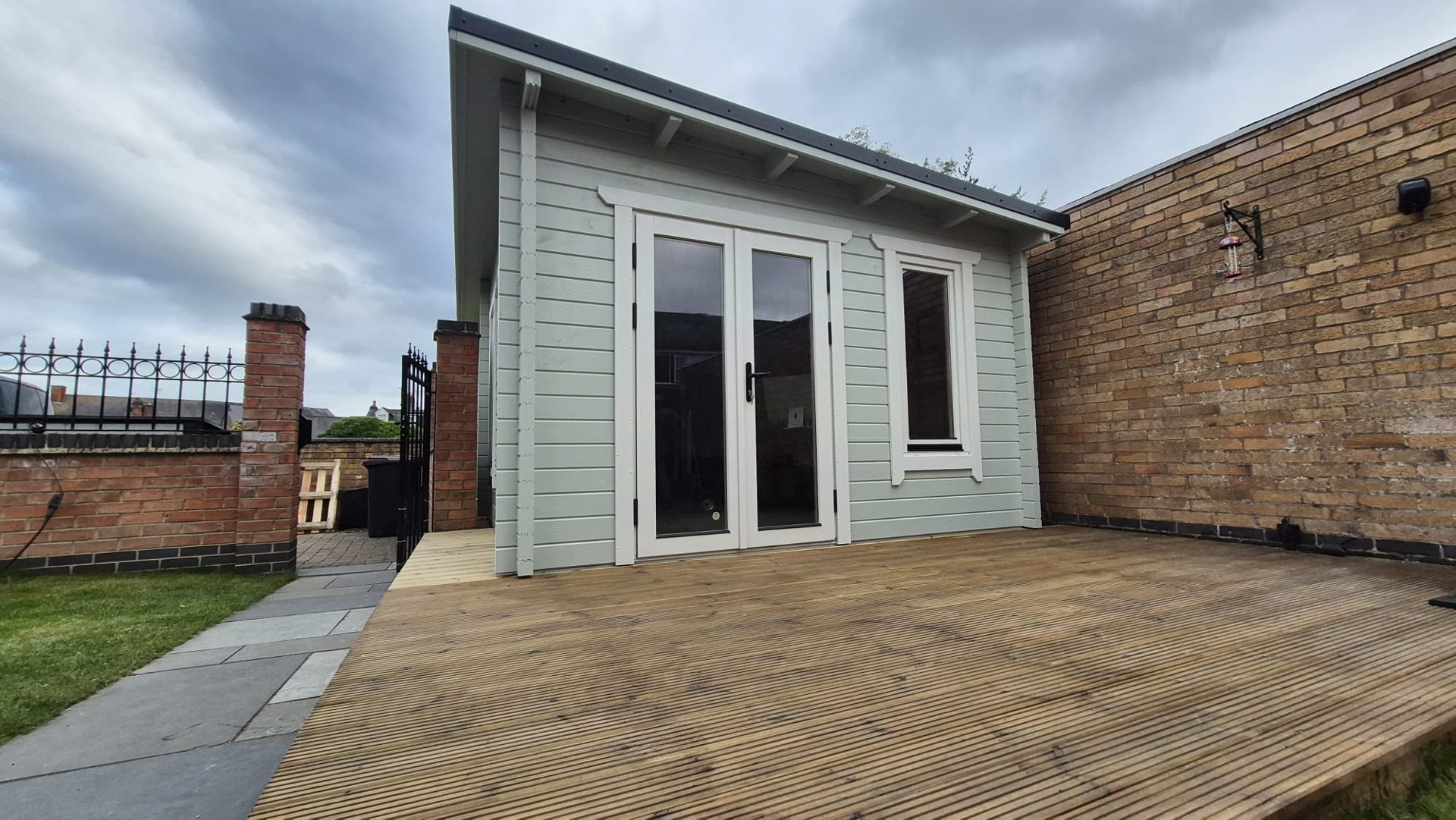 Chalet de jardin Eurodita peint en gris clair, avec une double porte vitrée, sur une terrasse en bois