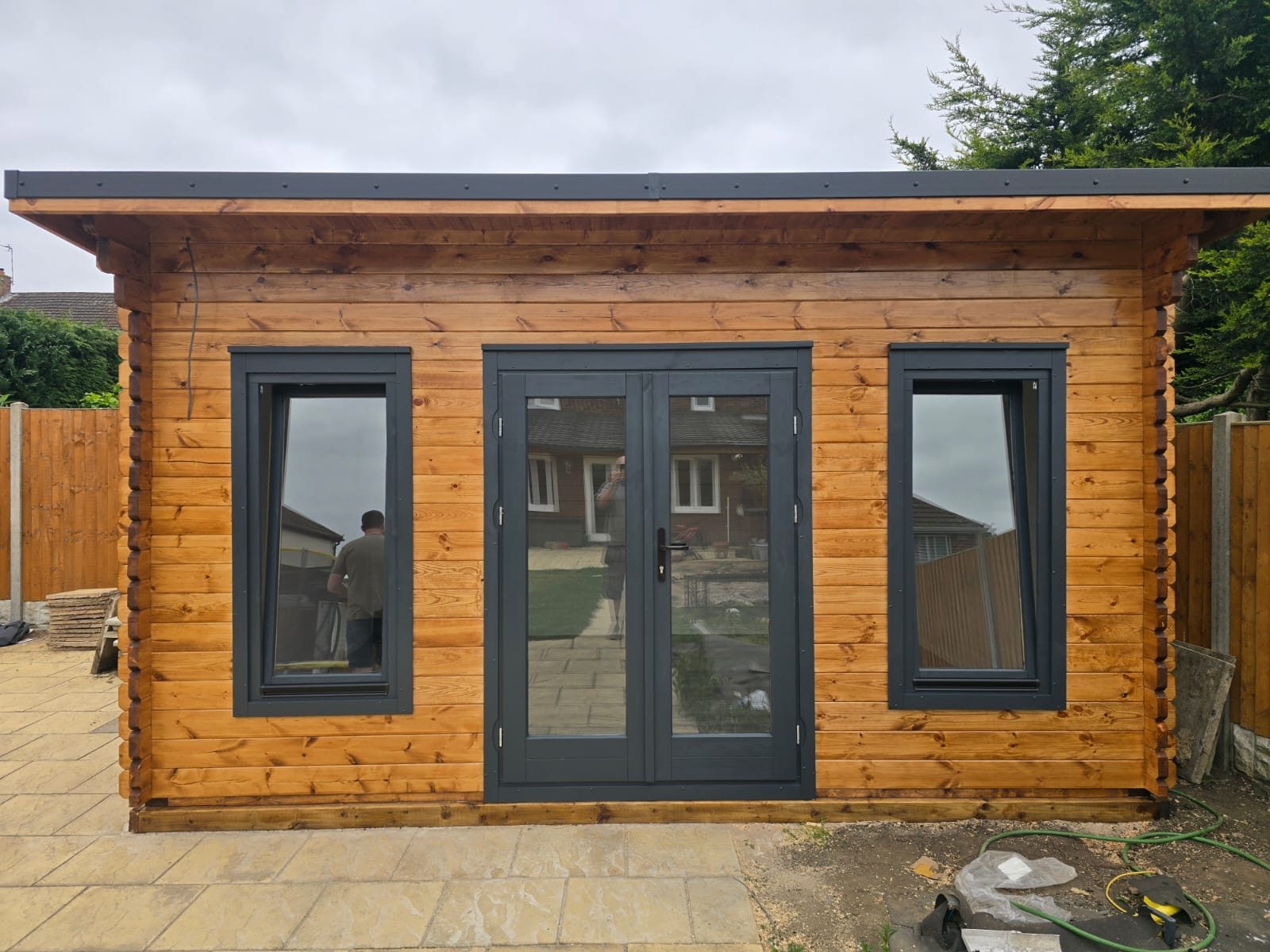 Pent-roof garden office in stained timber with dark window frames, photographed on a delivered order