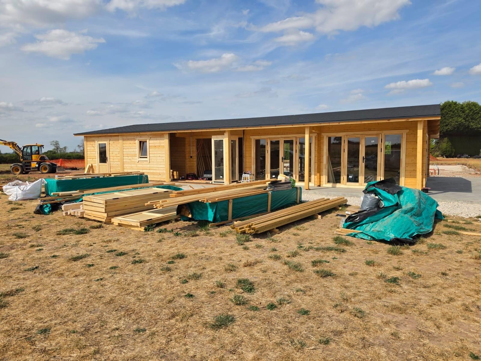 Larger single-storey timber building with a full-length veranda, photographed during site works on a delivered order