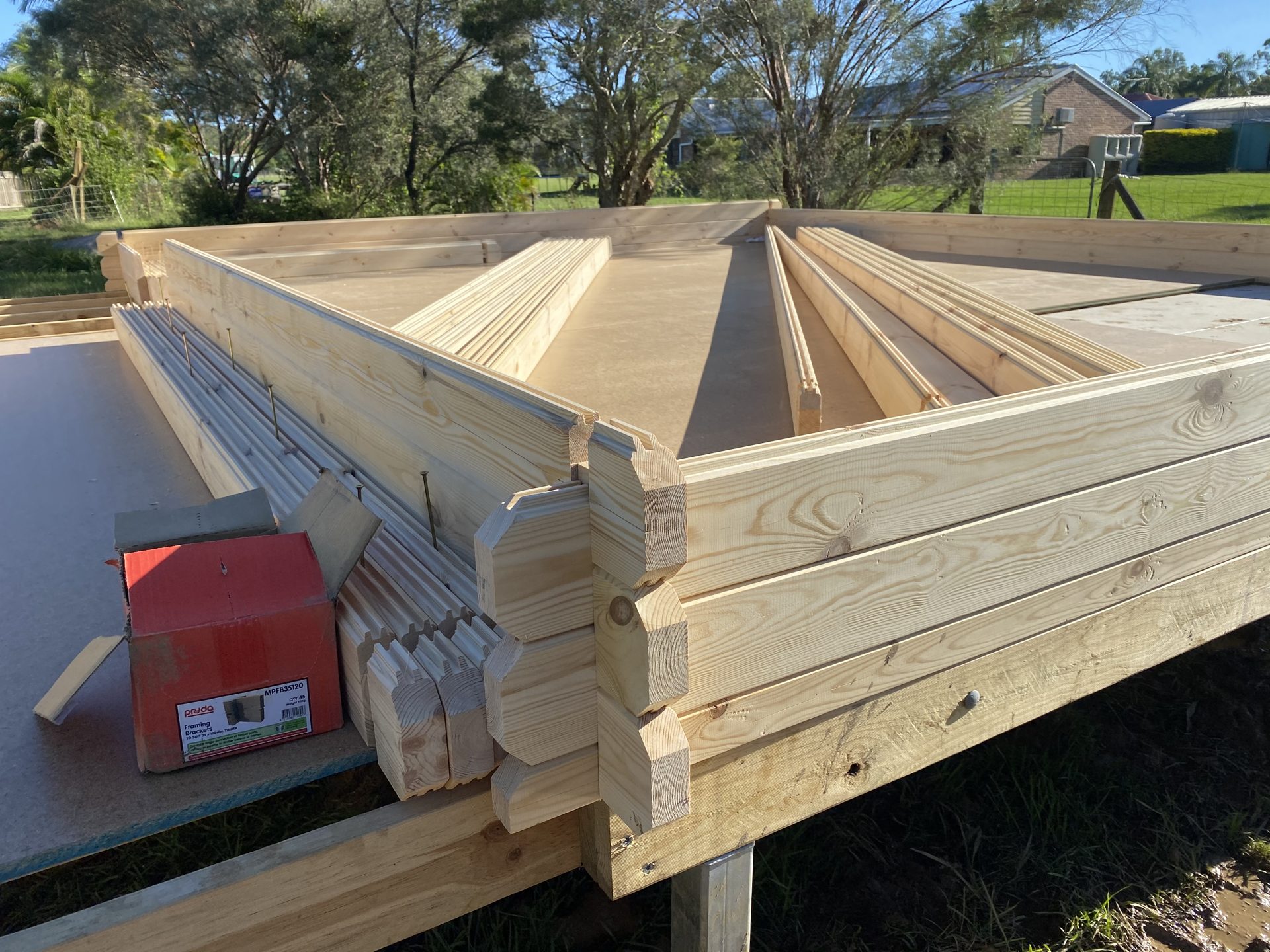 CNC-machined solid wall logs with interlocking corner joints stacked on site