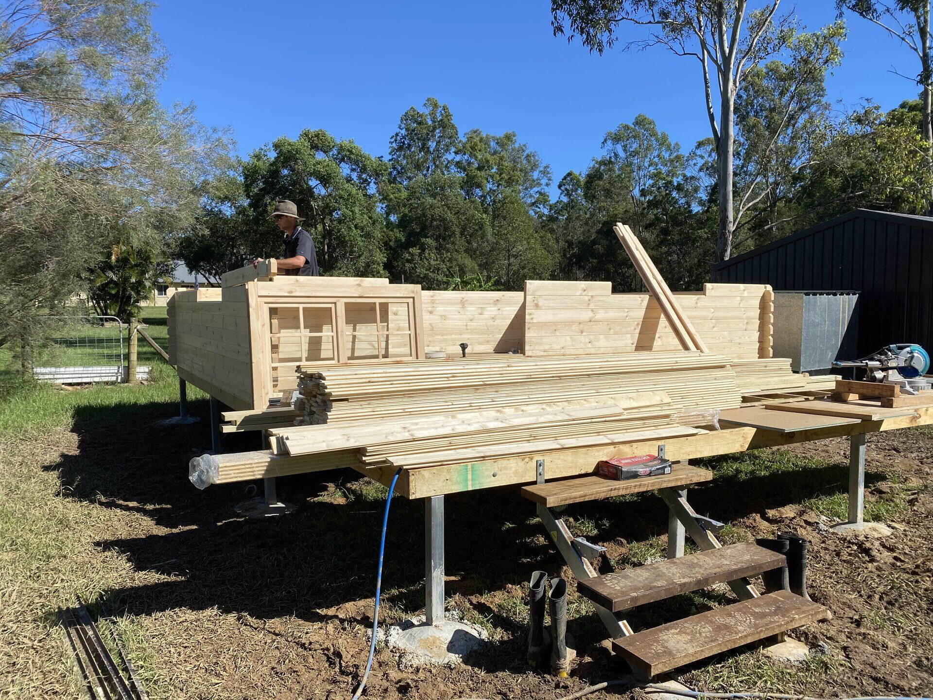 First wall courses of a solid log cabin kit being laid by the buyer's crew