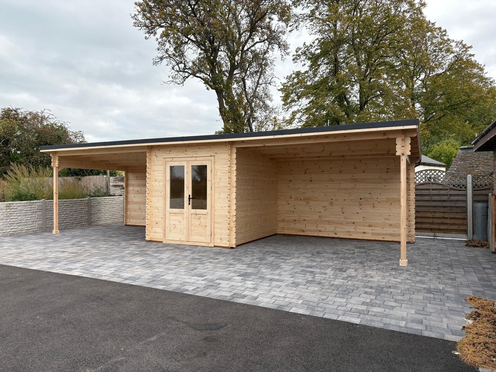 Log cabin with an attached open carport on a block-paved drive